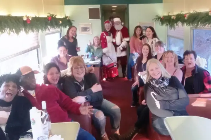 Group of people on a decorated train with Santa and Mrs. Claus.