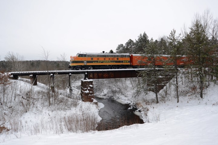 a train crossing a bridge over some snow